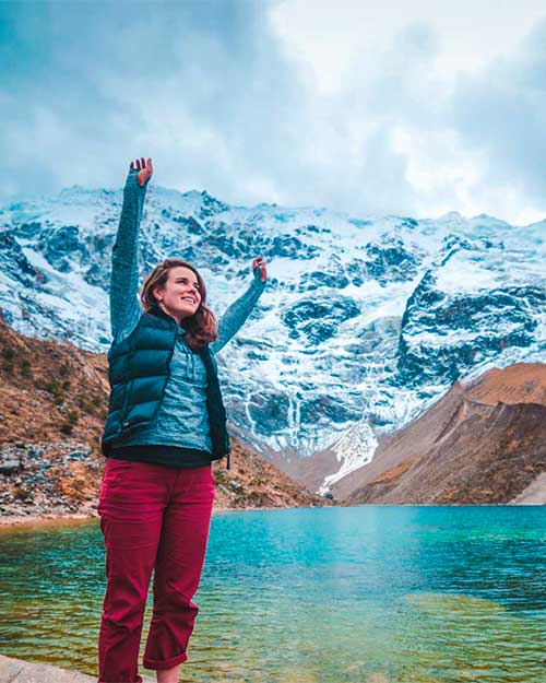 Woman raising her arms in the Humantay Lake